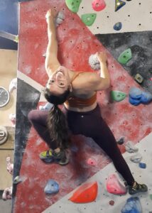 Young woman on a bouldering wall smiling into the camera
