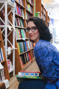 Woman kneeling with stack of books in bookstore