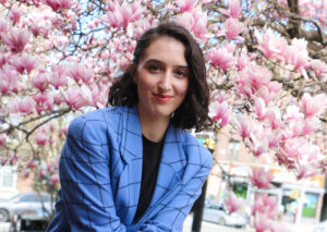 Woman in blue blazer in front of pink flowers