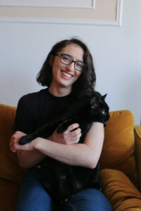 Young woman with black cat looking right