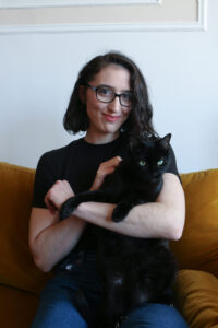 Young woman with black cat looking ahead