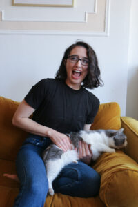 Woman laughs while a gray and white cat tries to escape her arms
