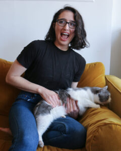 Woman laughs while a gray and white cat tries to escape her arms
